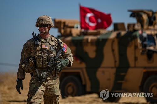 지난달 시리아 북부 국경 지역에서 터키군 장갑차량 옆을 지나는 미군 부대원 [AFP=연합뉴스 자료사진]