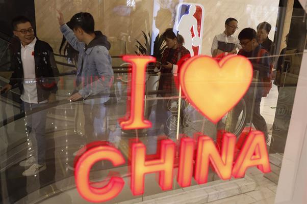 9일(현지시간) 중국 시민들이 베이징에 있는 미국프로농구(NBA) 스토어에 위치한 NBA 로고 옆을 지나가고 있다. 베이징=EPA 연합뉴스