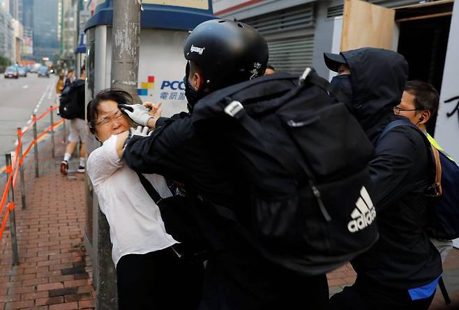 한 여성이시위대의 마스크를 벗기려 하자 주변의 시위대와 뒤엉켜 몸싸움이 벌어졌다. [로이터=연합뉴스]