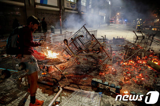 칠레에서 시위에 나선 사람들이 쇼핑카트 등에 불을 지르고 있다. © 로이터=뉴스1