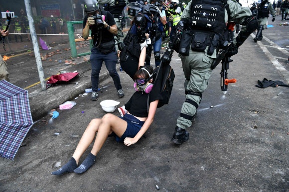 홍콩 경찰 이공대 진압… 질질 끌려가는 시위 여성 - 홍콩 시위대가 민주화 투쟁의 ‘마지막 보루’로 여긴 이공대에 대한 경찰의 진압 작전이 개시된 18일 한 여성이 교정을 탈출하려다 경찰에 붙잡혀 끌려 나가고 있다. 경찰이 시위대를 향해 수차례 실탄을 발사하는 등 홍콩 사태가 갈수록 나빠지자 홍콩 교육 당국은 지난 14일 시작한 휴교령을 19일까지 연장했다. 홍콩 AFP 연합뉴스