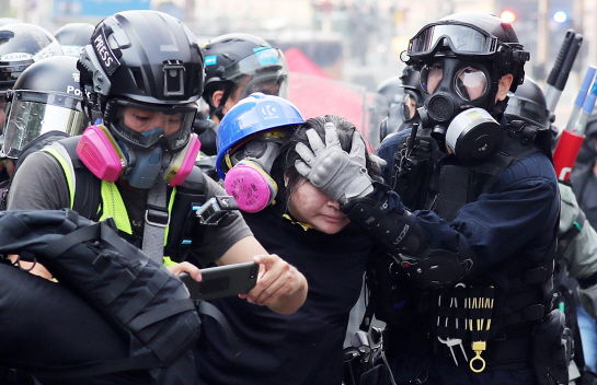 지난 18일(현지시간) 오후 홍콩 이공대에서 경찰이 시위대를 연행하고 있다 (사진=뉴시스)