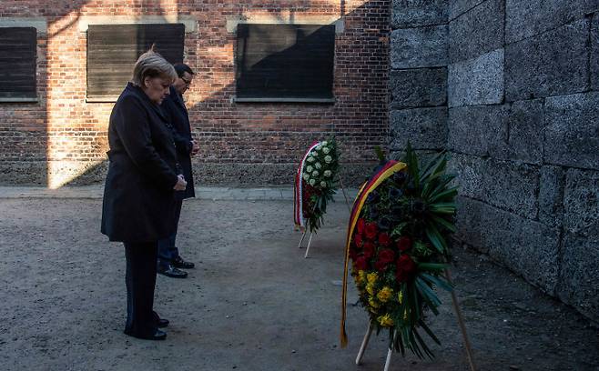 앙겔라 메르켈 독일 총리(앞)가 6일(현지시간) 마테우시 모라비에츠키 폴란드 총리와 함께 아우슈비츠-비르케나우 강제수용소의 ‘죽음의 벽’ 앞에서 헌화하고 묵념하고 있다. AFP연합뉴스