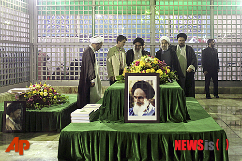 【테헤란=AP/뉴시스】하산 로하니 이란 대통령 당선인(오른쪽에서 3번째)이 16일(현지시간) 테헤란 외곽에 있는 '이슬람 혁명의 아버지’ 아야톨라 호메이니의 사원을 방문에 그의 묘에서 기도하고 있다. 앞에 호메이니의 사진이 보인다. 로하니 당선인이 이날 이란 심각한 경제 문제는 하룻밤 만에 해결할 수 있는 문제가 아니라고 밝혔다.  2013.06.17