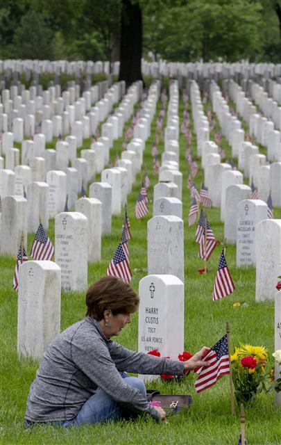 미국에서 시신을 묻거나 태우는 대신 땅에 도움이 되는 방식으로 처리하는 ‘시신 퇴비화’가 5월부터 시행되는 가운데 한 여성이 버지니아주 알링턴 국립묘지에 안장된 남편의 묘비 옆에 앉아 있다. 미국에서는 남북전쟁 당시 전사한 군인의 시신을 보존하기 위해 방부 처리를 시작했는데, 환경론자들은 “이 방식이 여러 가지 문제를 낳고 있다”고 비판한다.UPI 연합뉴스