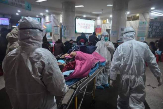 신종 코로나바이러스의 발원지인 중국 후베이성 우한에 있는 적십자병원에서 방호복을 입은 의료진이 지난 25일 환자를 실어 나르고 있다. 우한=AFP연합뉴스