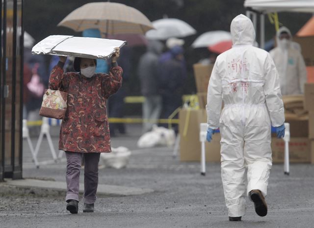 2011년 동일본 대지진으로 후쿠시마 원전 폭발 사고가 발생, 최악의 방사선 유출이 우려되는 일본 후쿠시마현 고리야마시 일대에서 마스크를 착용한 여성이 방사선 물질을 피하기 위해 머리 위에 보호구를 얹고 지나고 있다. 후쿠시마=AP연합뉴스