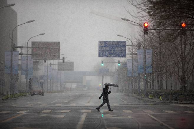 지난 14일 중국 베이징에서 마스크를 쓴 한 남성이 인적이 끊긴 교차로를 건너가고 있다. 사진 AP·연합뉴스