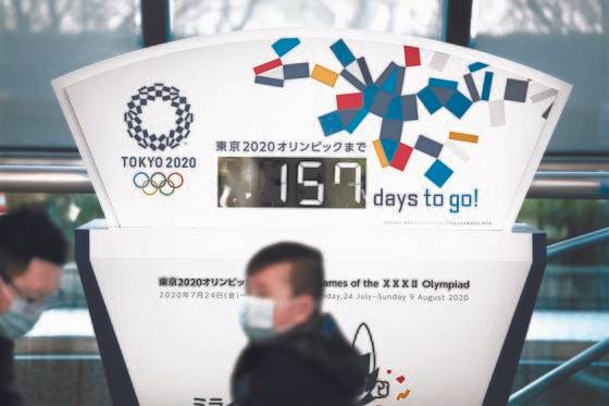 지난 18일 일본 도쿄 도심에 설치된 2020 도쿄올림픽 카운트다운 조형물 앞을 마스크를 쓴 시민들이 지나가고 있다. 올림픽이 5개월 앞으로 다가온 가운데 도쿄올림픽 조직위원회는 신종 코로나바이러스 감염증(코로나19) 확산을 크게 우려하고 있다. [AP=연합뉴스]