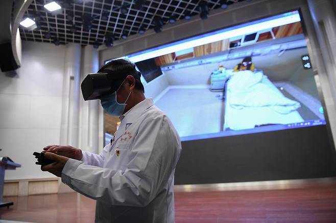 24일 중국 운난성 쿤밍시의 한 병원에서 의료진이 가상현실(VR) 고글을 착용한 채 코로나19 환자를 체크하고 있다. 로이터 연합뉴스