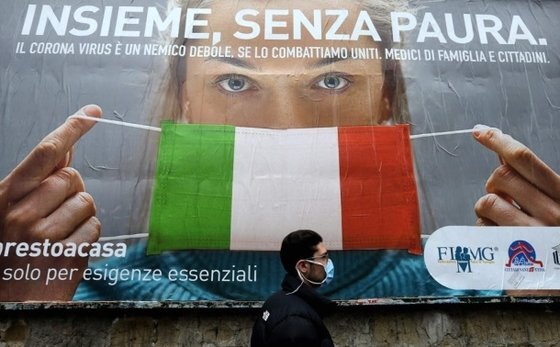 이탈리아 나폴리 거리에서 22일(현지시간) 이탈리아 국기를 신종 코로나바이러스 감염증(코로나19) 예방 마스크로 표현한 대형 포스터 앞으로 한 남성이 지나고 있다. AFP=연합뉴스