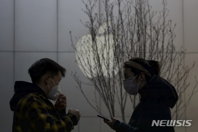 [베이징=AP/뉴시스]2월26일(현지시간) 중국 베이징에서 마스크를 쓴 쇼핑객들이 애플 로고 앞을 지나고 있다. 애플은 신종 코로나바이러스 감염증(코로나19) 확산을 우려해 중화권을 제외한 전 지역의 매장을 닫기로 했다고 14일 밝혔다. 2020.03.14.
