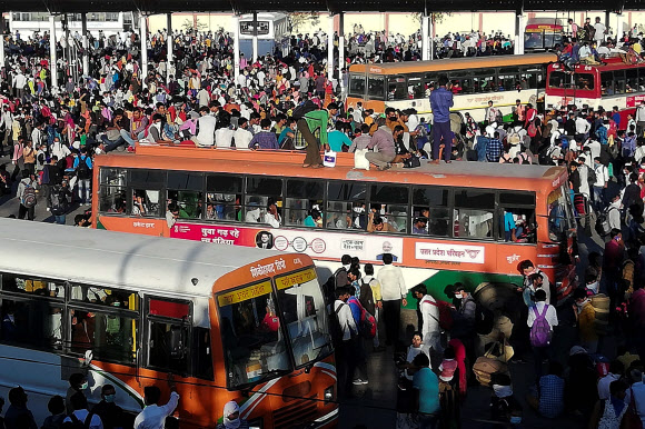 28일(현지시간) 인도 뉴델리에서 신종 코로나바이러스 (COVID-19)의 확산을 제한하기 위해 25일부터 21일간 국가봉쇄령 기간 동안 고향으로 가는 버스에 탑승하기 위해 이주 노동자들이 버스 정류장 밖에 몰려들고 있다. AFP 연합뉴스