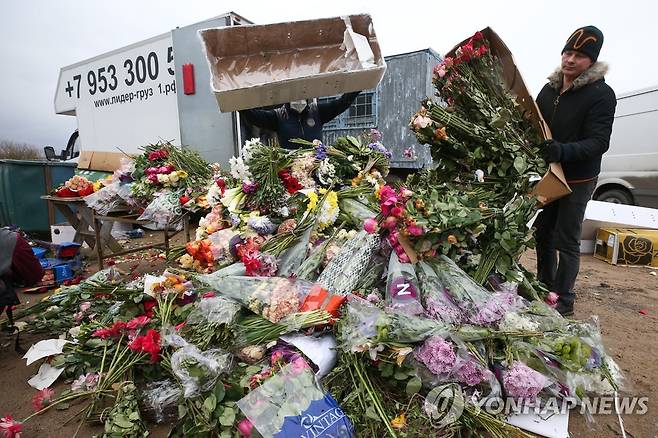 13일(현지시간) 러시아에서 한 꽃집 주인이 코로나19로 안팔린 꽃들을 내다 버리고 있다. [타스=연합뉴스]