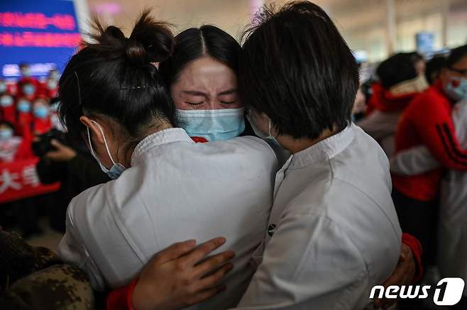 지난 8일 코로나19 진원지로 76일만에 봉쇄령이 해제된 후베이성 우한 텐허 공항에서 지린성과 우한의 의료진이 포옹을 하며 울고 있다. © AFP=뉴스1 © News1 우동명 기자