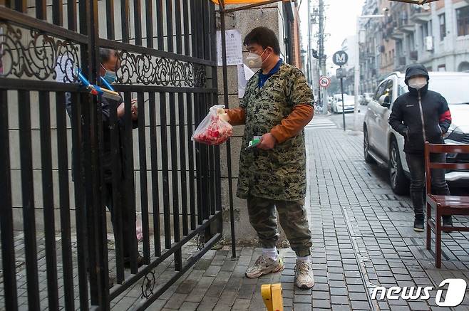 지난달 코로나 19 감염증 발원지인 후베이성 우한에서 마스크 쓴 행상인이 주민에게 음식을 배달하고 있다. © AFP=뉴스1 © News1 우동명 기자