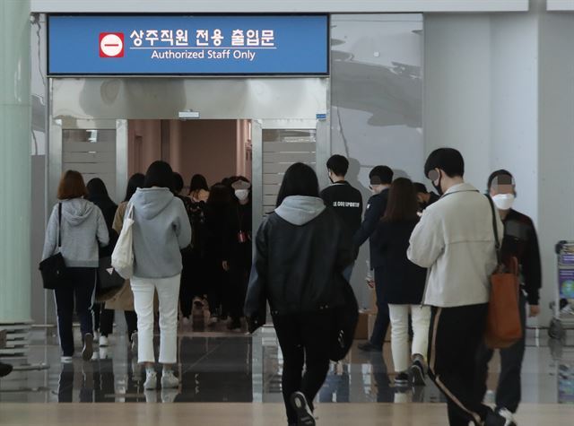 21일 오후 인천국제공항 제2여객터미널에서 상주 직원들이 전용 출입문으로 향하고 있다. 연합뉴스