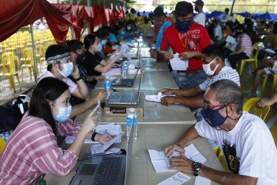 지난달 30일 필리핀의 케손시티에서 주민들(오른쪽)들이 정부의 코로나19 현금 지원을 받기 위해 공무원과 상담하고 있다. EPA=연합뉴스