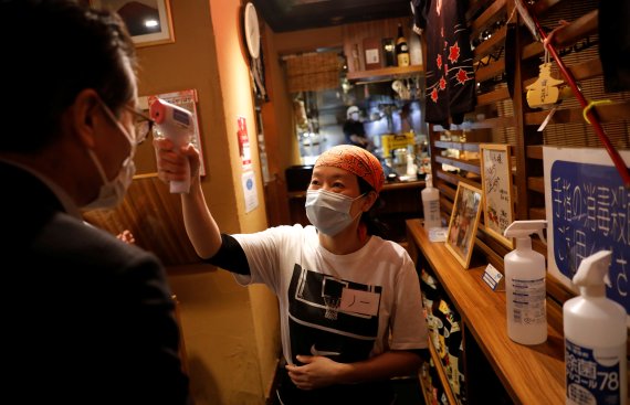 도쿄의 한 식당의 종업원이 손님의 열을 체크하고 있다. 로이터 뉴스1