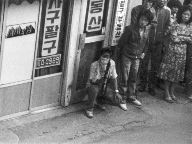 계엄군이 광주 금남로에서 시위대를 향해 집단 발포를 한 1980년 5월 21일 주변 골목에서 소총을 든 젊은이와 시민들이 벽에 몸을 바짝 붙인 채 무언가를 기다리고 있다. 이날 집단발포 후 자체 무장을 시작한 시위대는 계엄군과 산발적인 시가전을 벌였다. 한국일보 특별취재팀