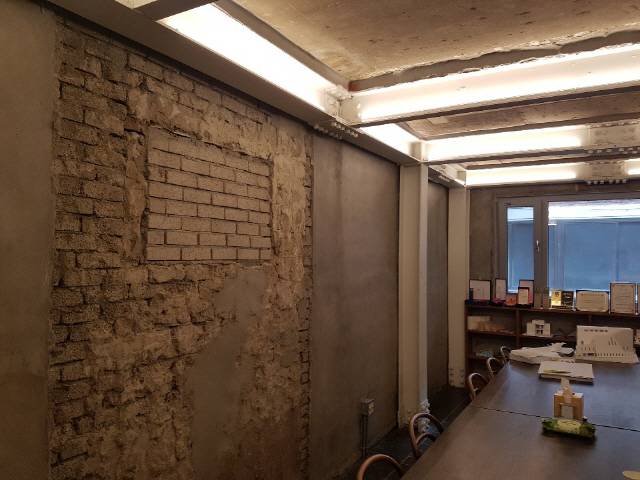 1층 살롱의 벽면과 천장. 준공 당시 마감의 흔적이 다양하게 남았고 지난해 내력벽을 철거하면서 보강한 흰색 스틸빔도 고스란히 노출했다. 지난 1987년부터 2019년까지 건축물의 역사가 공존한다./사진=김흥록기자