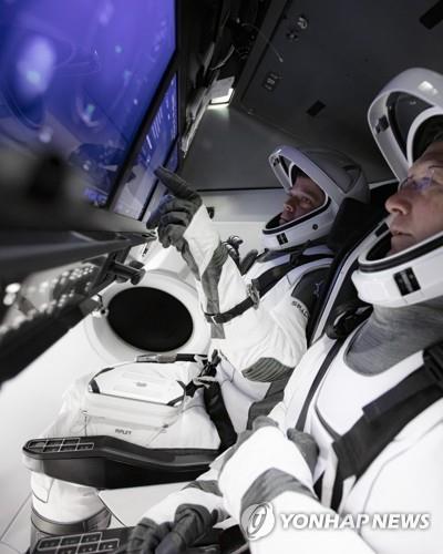 크루 드래건 시뮬레이터 앞의 두 우주 비행사 크루 드래건 캡슐의 첫 유인 비행시험을 맡은 더그 헐리와 봅 벤켄 우주비행사가 터치스크린으로 된 조종판 앞에서 스페이스X 측이 마련한 우주복을 입고 캡슐 작동 훈련을 하고 있다. [AP/SpaceX = 연합뉴스]