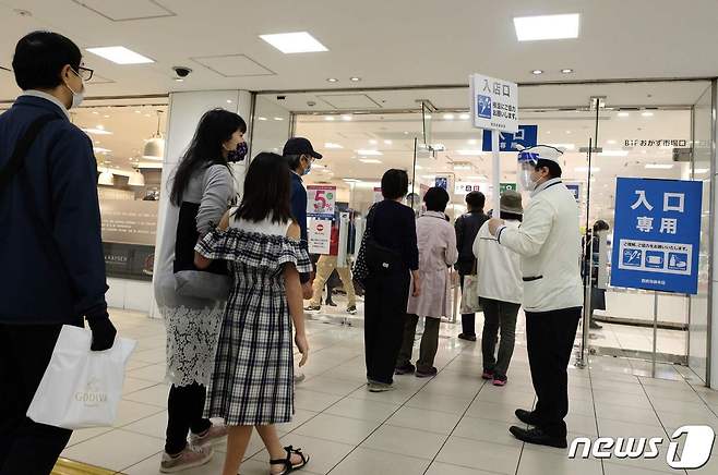 23일 일본 도쿄시내 세이부 이케부쿠로 백화점을 찾은 고객들이 발열검사를 받기 위해 줄지어 서 있다. © AFP=뉴스1