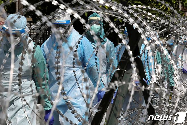 방호복을 입은 말레이시아 의료진이 코로나19로 봉쇄된 현장을 살피고 있다. © 로이터=뉴스1