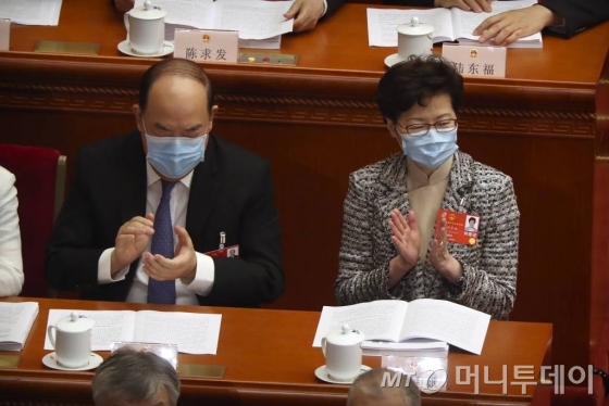 [베이징=AP/뉴시스]22일(현지시간) 중국 베이징 인민대회당에서 중국 최대 정치 행사인 전국인민대표회의(전인대)가 열리고 있는 가운데 캐리 람 홍콩 행정장관(오른쪽)이 신종 코로나바이러스 감염증(코로나19)을 막기 위해 마스크를 쓴 채 박수를 치고 있다.  2020.05.22.