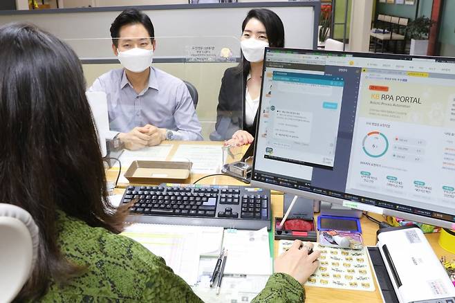 KB국민은행 여의도영업부 직원이 고객과 상담 중에 대출 서류, 급여이체 등록 여부를 RPA(Robotic Process Automation·로봇 처리 자동화) 포털과 RPA 챗봇으로 확인하는 모습./사진제공=KB국민은행