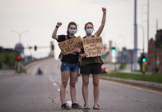 5월 26일 미국 메네소타주 미니애폴리스에서 두 명의 여성이 '흑인들의 생명도 중요하다' '그의 이름은 조지 플로이드였다'는 팻말을 들고 조지 플로이드의 사망에 항의하는 사위를 벌이고 있다.AFP=연합뉴스