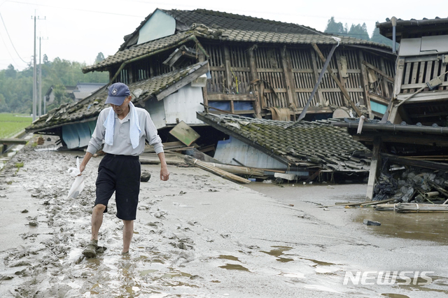 [구마모토=AP/뉴시스]지난 5일 일본 구마모토현 구마무라에 내린 폭우로 주택들이 파손된 가운데 한 남성이 흑탕물이 휩쓴 길을 걷고 있다. 6일 기준 구마모토에서는 27명이 사망했다. 2020.07.06.