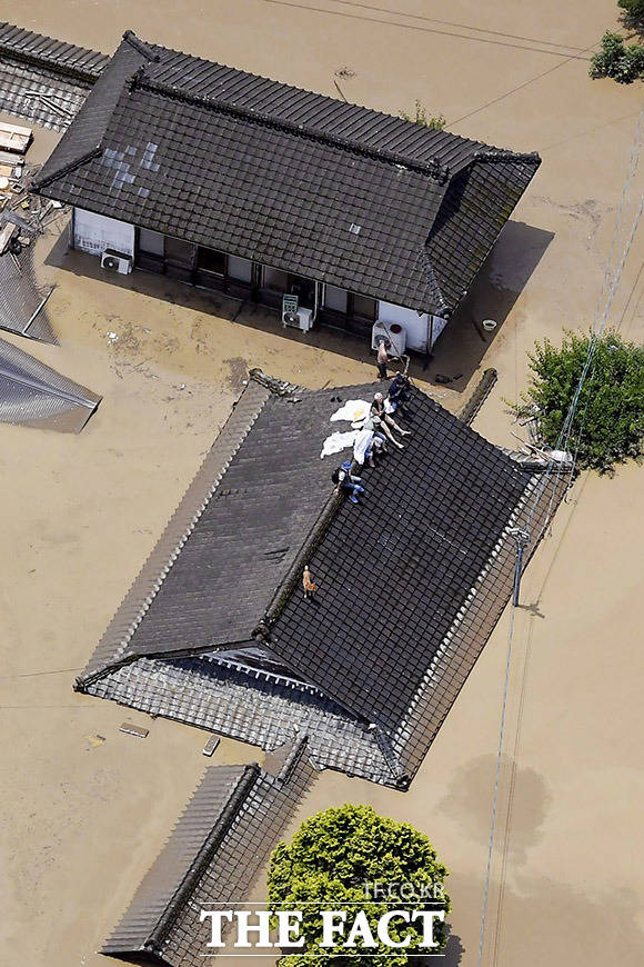 '지붕 위로 탈출' 구마모토현 히토요시에서 폭우로 가옥이 물에 잠기자 주민들이 지붕 위에 올라가 구조를 기다리고 있다.