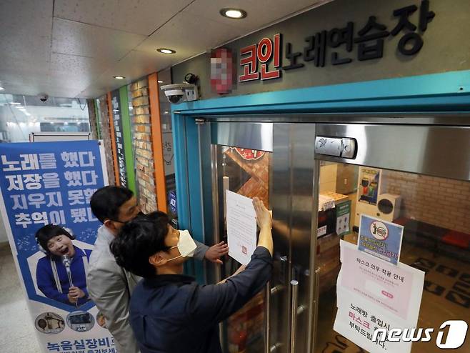 (서울=뉴스1) 허경 기자 = 신종 코로나바이러스감염증(코로나19) 확산을 우려해 서울시가 모든 코인노래방에 대해 사실상 영업중단을 명령한 22일 서울 종로구의 한 코인노래방 입구에 종로구청 관계자들이 집합금지안내문을 붙이고 있다. 2020.5.22/뉴스1