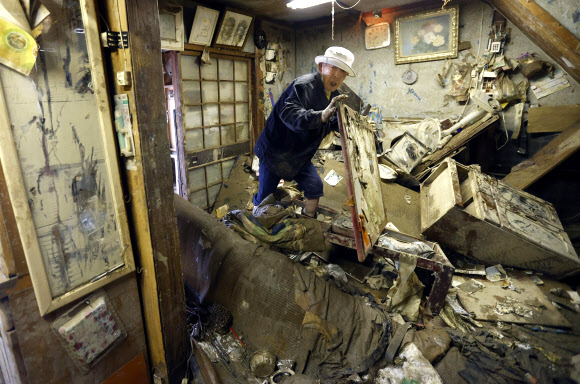 일본 폭우 피해 확산 - 12일 일본 남부 구마모토 히토요시에서 폭우로 집이 붕괴된 가운데 고령의 남성이 약을 찾고 있다. 일본은 집중 폭우로 하천이 범람하고 산사태가 발생하면서 실종된 사람들을 여전히 수색하고 있다.AP 연합뉴스 2020-07-12 12:49:13