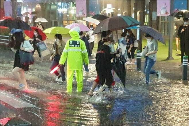 23일 부산에 내린 폭우로 물에 잠긴 부산 서면에서 시민들이 경찰 안내에 따라 길을 건너고 있다. (사진=부산경찰청 제공)