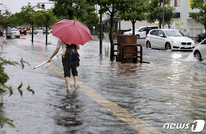 일본 규슈(九州) 북부 사가(佐賀)현에서 한 여성이 물에 잠긴 도로 위를 걷고 있다. © 로이터=뉴스1