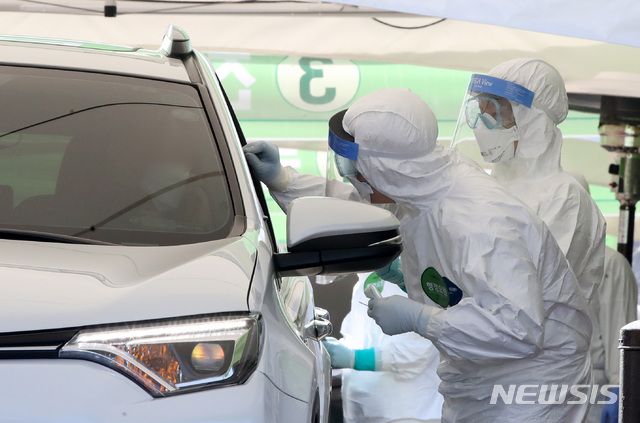 의료진들이 서울 송파구 잠실주경기장에 마련된 드라이브 스루 코로나19 선별진료소에서 차량에 탑승한 시민을 검사하고 있다.
