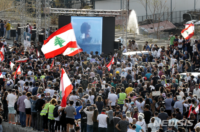 [베이루트=AP/뉴시스]11일(현지시간) 레바논 베이루트 폭발 참사 현장에서 희생자들을 기리는 추모식이 열려 참석 시민들이 거대한 폭발이 일어난 순간을 대형 화면으로 지켜보고 있다. 2020.08.12.