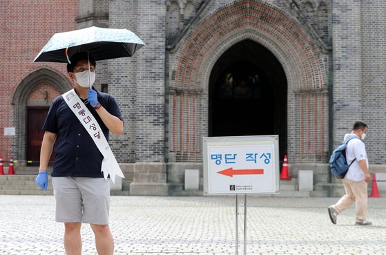 수도권 코로나19 재확산으로 사회적 거리두기 2단계가 16일부터 시행된 가운데 이날 서울 명동성당 관계자가 신자들에게 출입자 명단작성을 안내하고 있다. 최정동 기자
