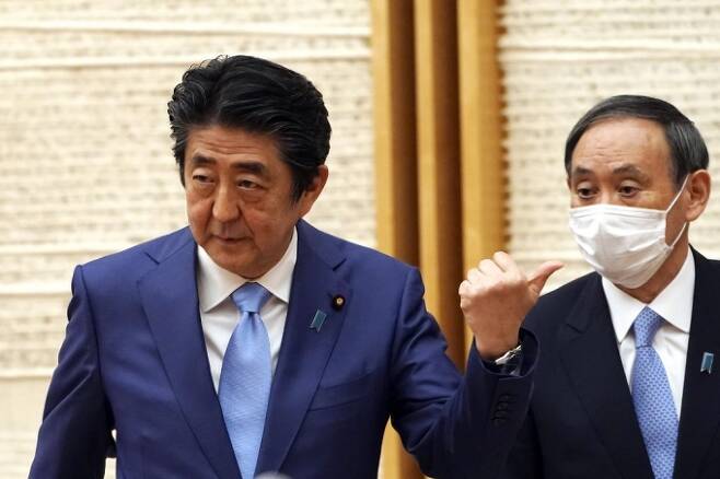 아베 신조 일본 총리(왼쪽)과 스가 요시히데 관방장관(오른쪽). 코로나19 재확산의 원흉으로 꼽히는 '고투 트래블' 캠페인을 스가 장관이 밀어붙였다는 보도가 나왔다. /AFPBBNews=뉴스1