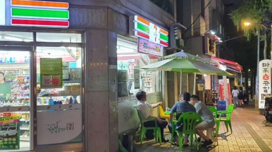 서울 동대문구 회기동에 위치한 편의점 앞 야외 테이블에서 고객들이 술을 마시고 있다. 코로나19 감염 우려 탓에 평소보다 테이블 간 거리는 멀어졌지만 마스크를 쓰고 있는 이들은 찾아볼 수 없었다.