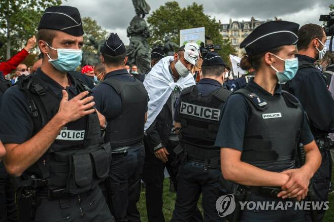 지난달 29일 파리 나시옹 광장에서 마스크를 벗은 한 시위 참가자에게 프랑스 경찰관이 과태료 처분을 내리고 있다. [EPA=연합뉴스 자료사진]