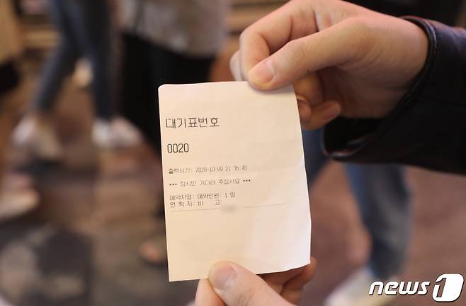 9일 밤 한 시민이 주점에서 받은 대기번호표를 취재진에게 보여주고 있다.2020.10.9/© 뉴스1 박세진 기자