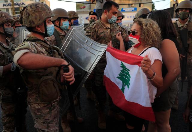 5일 레바논 수도 베이루트에서 국기를 든 반정부 시위대와 진압 군인들이 대치하고 있다. 베이루트=AP 연합뉴스