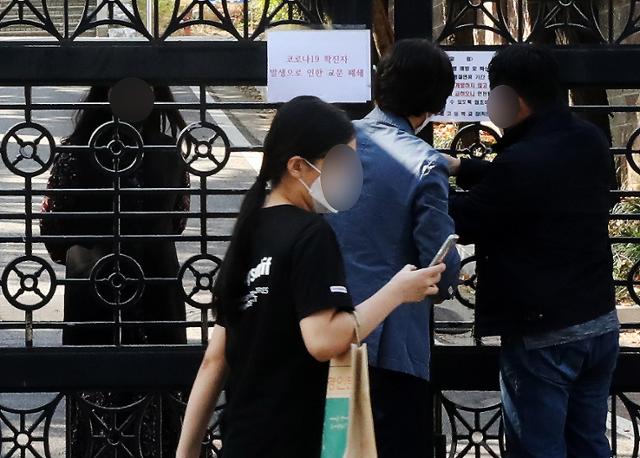 경기 부천지역에 신종 코로나바이러스 감염증(코로나19) 확진자가 속출한 지난 20일 오후 확진자가 나온 부천시 모 고등학교에서 학교 관계자들이 출입문을 폐쇄하고 있다. 뉴스1