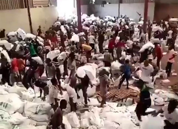 24일(현지시간) 나이지리아 중앙도시 조스 소재 정부창고에 난입한 시위대 수천 명이 건물 꼭대기로 기어 올라가 지붕을 뜯고 창고에 보관된 쌀과 파스타 자루를 약탈했다./사진=트위터