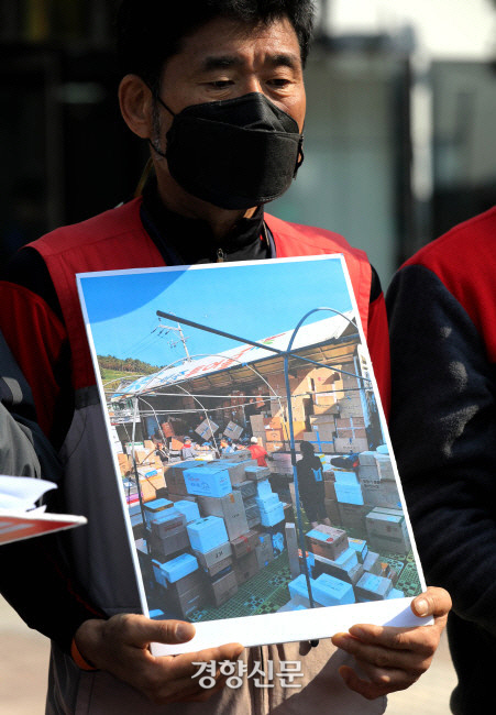 지난 26일 서울 중구 롯데글로벌로지스 본사 앞에서 열린 기자회견에 참석한 전국택배연대 노조원이 김해 지역의 택배 물류 분류작업 실태를 찍은 사진을 공개하고 있다. 김창길 기자