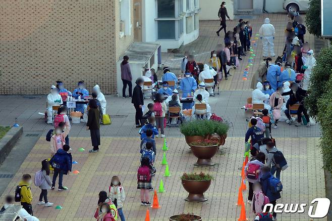 광주 지역에서 신종 코로나바이러스 감염증(코로나19) 확진자가 속출하고 있는 가운데 16일 오후 광주 북구 하백초등학교에서 해당 학교 학생들이 진단 검사를 받기 위해 길게 줄지어 서있다. 이날 오후 해당 학교 학생 2명이 코로나19에 확진돼 시는 선별진료소를 설치, 전수검사를 진행하고 있다.2020.11.16 /뉴스1 © News1 정다움 기자