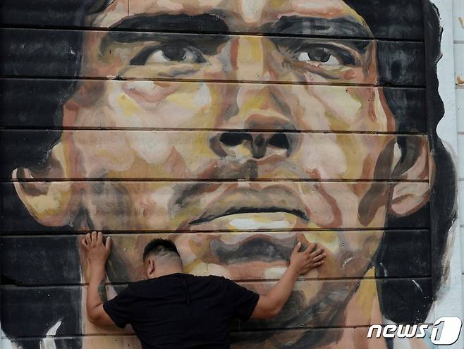 사망 소식을 접한 한 축구팬이 마라도나의 벽화 앞에서 흐느끼고 있다. © 로이터=뉴스1